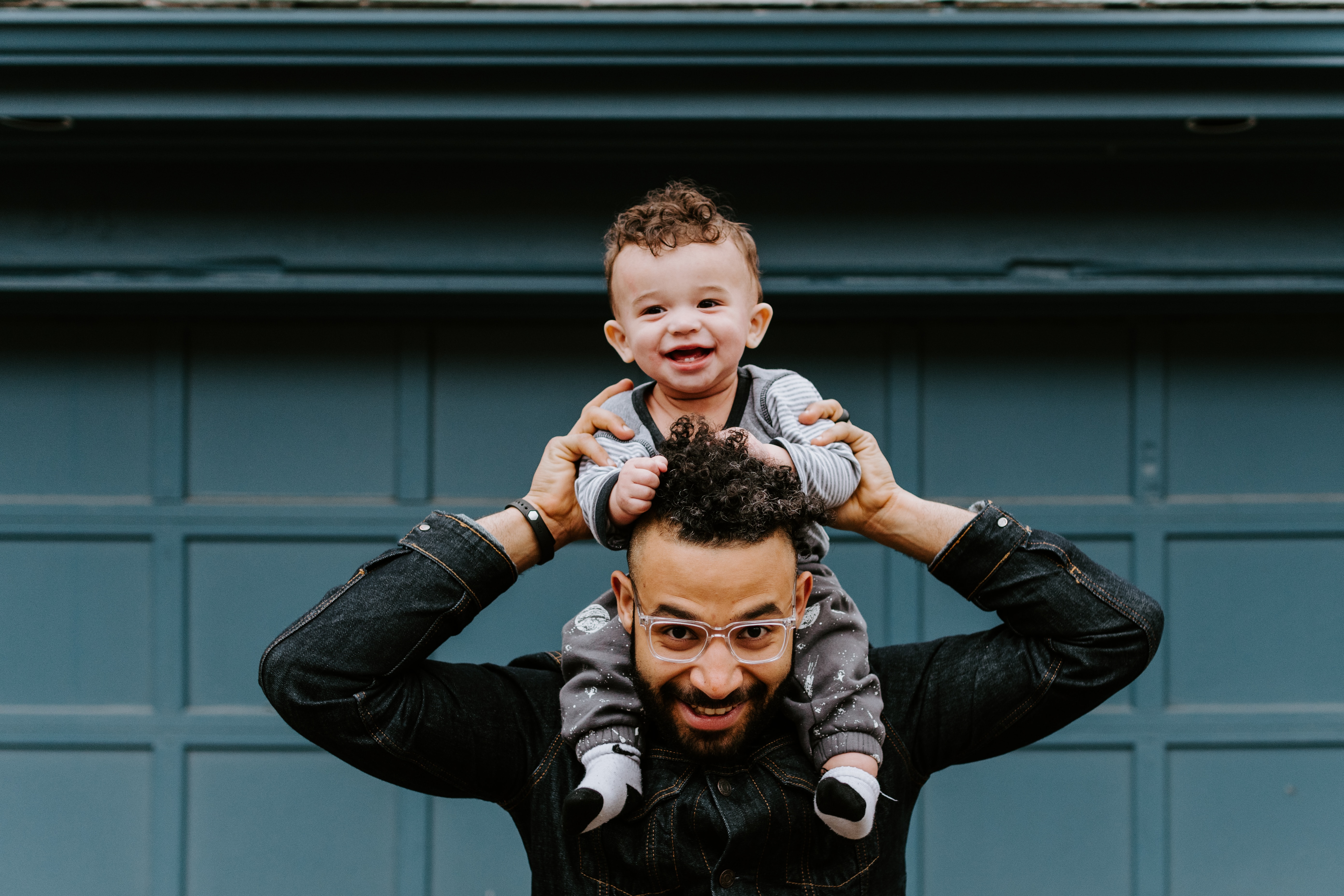 dad with young child on his shoulders, both smiling