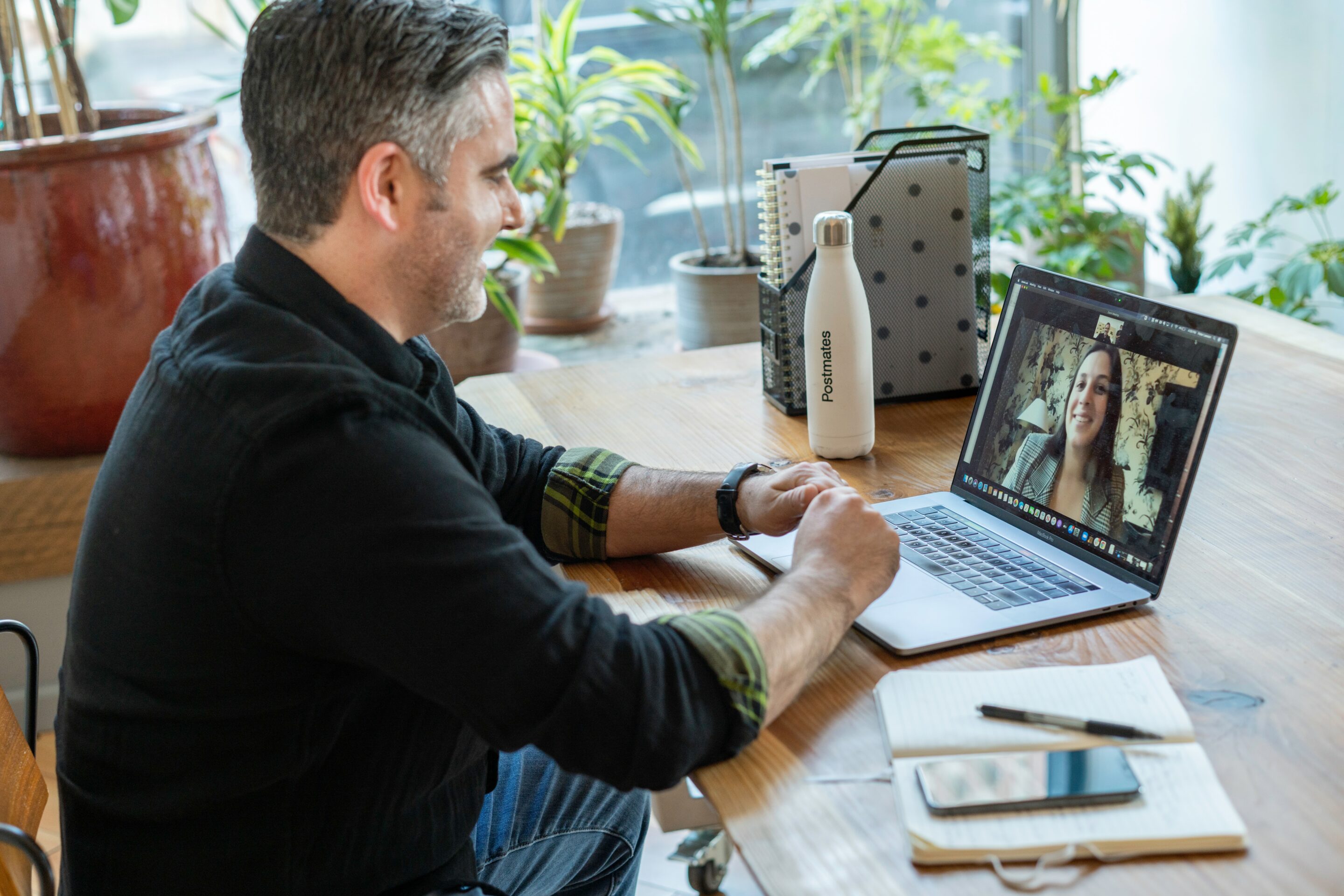 man on zoom sitting at a desk with plants in the background