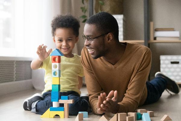 dad laying on the ground with his child, playing with blocks